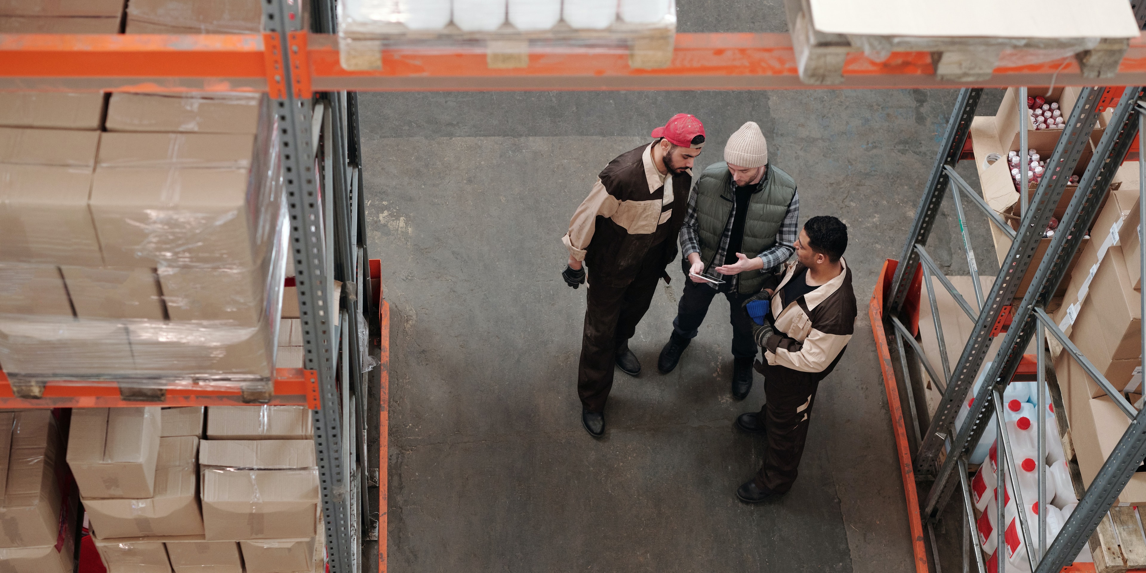 multi-warehouse-touchtribe Three guys who work in a warehouse are looking at tablet together.